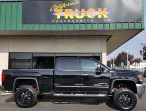 Side view of a black pickup truck with suspension lifts