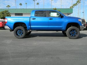 Side view of a blue pickup truck with matching blue wheels